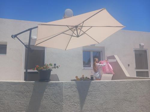 a woman standing under a large white umbrella at PAME apartments in Kámpos