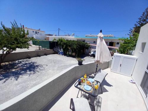 a table and chairs on a balcony with an umbrella at PAME apartments in Kámpos