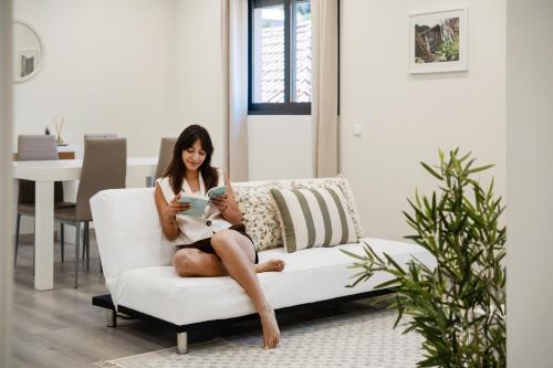 a woman sitting on a couch looking at her phone at Coração da Madeira by Homie in Curral das Freiras