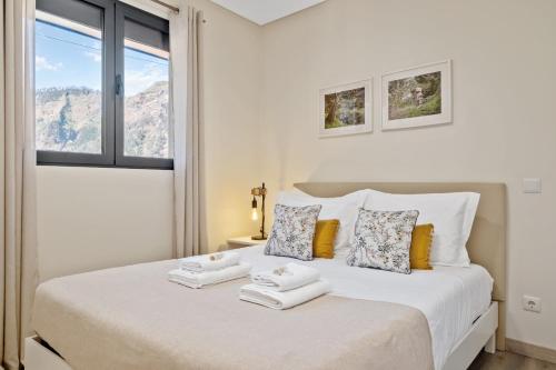 a white bedroom with a bed with towels on it at Coração da Madeira by Homie in Curral das Freiras