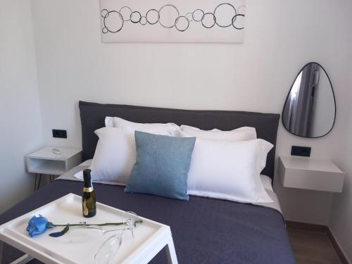 a bed with white pillows and a table with a bottle of wine at PAME apartments in Kámpos