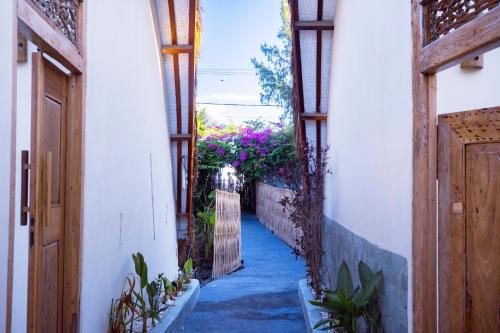 an alley way with flowers in a building at Coral Drift Beach Bungalow in Gili Air