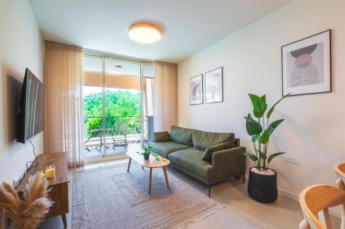 a living room with a green couch and a window at סי מיה - דירות מהממות במתחם נאות גולף in Caesarea