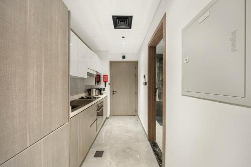 a kitchen with white cabinets and a hallway at Dubai Arjan Studio - Near Miracle Garden, Hills Mall & Attractions in Dubai