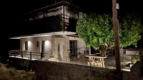 a small white house with a table and a tree at ANDRIANA Mountain Home - ASPRIAS 