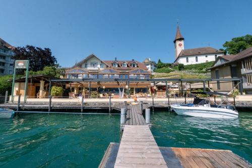 a boat is docked at a dock with a building at Room's at HAUS am SEE direkt am Thunersee gelegen mit SELF CHECK IN & digitaler Rezeption in Oberhofen am Thunersee