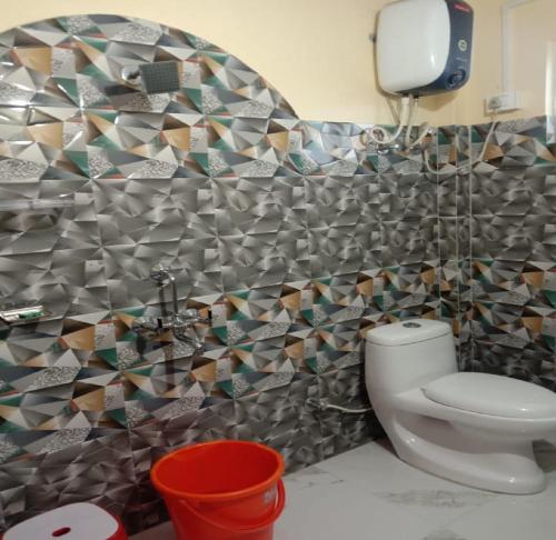 a bathroom with a toilet and a mosaic wall at Nawang Homestay By StayApart in Takdāh