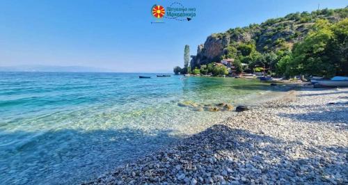 a beach with clear water and a rocky shore at Apartman Riste in Trpejca