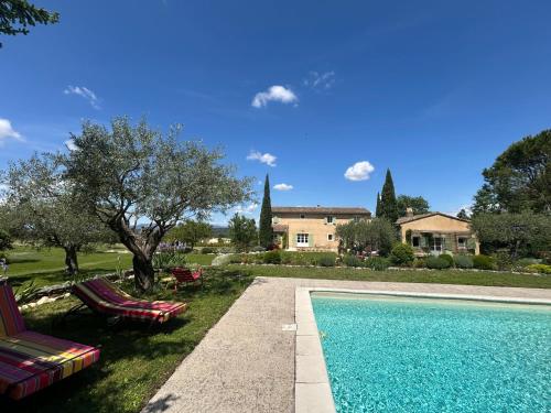 une piscine avec 2 chaises longues et une maison dans l'établissement Au Clair Ventoux B & B - SPA, à Saint-Didier