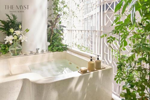 a bath tub with two bottles on it next to a window at The Myst Dong Khoi in Ho Chi Minh City