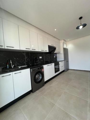a kitchen with white cabinets and a washer and dryer at La Brise in Chott Meriem