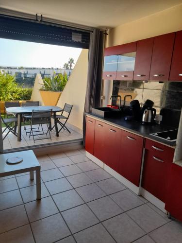 une cuisine avec des armoires rouges et une table sur un balcon dans l'établissement VILLAGE NATURISTE CAP D AGDE HELIOPOLIS D la maison d'andréas, au Cap d'Agde