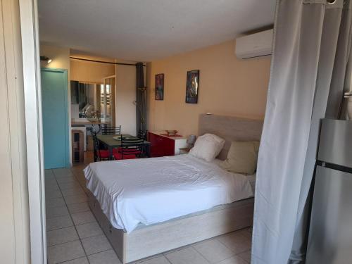 Cet appartement comprend une chambre avec un lit blanc et une cuisine. dans l'établissement VILLAGE NATURISTE CAP D AGDE HELIOPOLIS D la maison d'andréas, au Cap d'Agde