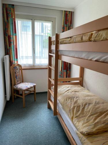 a bedroom with a bunk bed and a chair and a window at Le Petit Chalet Gentinetta in Leukerbad