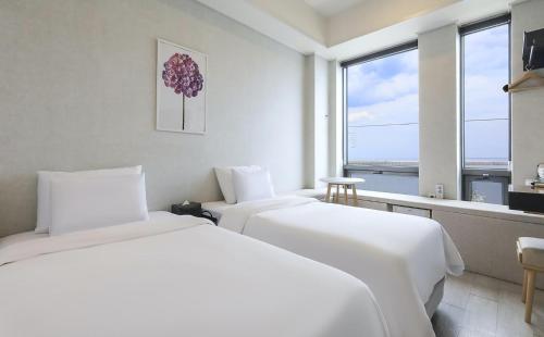 two beds in a white room with a window at Stay Hostel in Sokcho