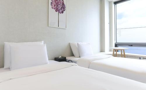 two white beds in a room with a window at Stay Hostel in Sokcho