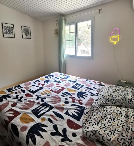 a bedroom with a bed with a comforter and a window at KaZandoli in Les Anses-dʼArlets