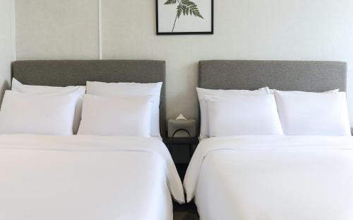 two beds in a hotel room with white pillows at Stay Hostel in Sokcho