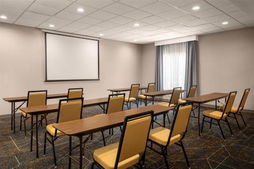 a conference room with tables and chairs and a screen at Hampton Inn & Suites Moline-Quad City Int'l Aprt in Moline