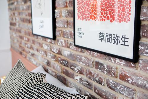 a brick wall with two framed posters on it at Settle Southampton - Stylish Self Check-In Rooms & Self Catering Suites in Southampton