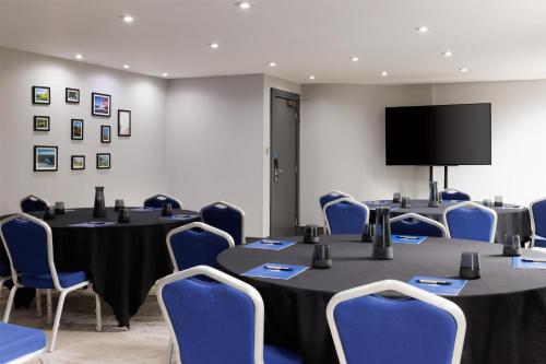 a conference room with tables and chairs and a flat screen tv at Hilton Cardiff in Cardiff