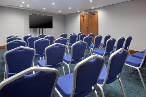 a conference room with blue chairs and a television at Hilton Cardiff in Cardiff