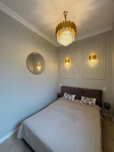 una camera da letto con un letto grande e un lampadario di Centre GRANT Apartment a Klaipėda