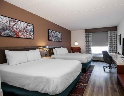 a hotel room with two beds and a desk at Hilton Garden Inn Hattiesburg in Hattiesburg