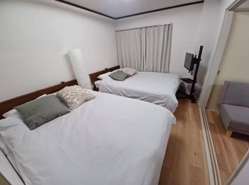 東京にあるnagumobiru202のソファのある小さな部屋にベッドが2つと、ベッドが2つある部屋