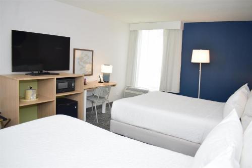 a hotel room with two beds and a flat screen tv at Hampton Inn St. Louis Southwest in Fenton
