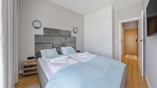 a white bedroom with a large bed with blue pillows at Słoneczna Dolina, Sun & Snow in Jastrzębia Góra