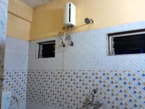 a tiled bathroom with a sink and two windows at Dream Residency Near Chinar Park in kolkata