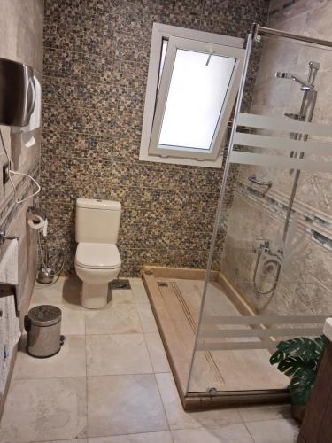 a bathroom with a shower and a toilet and a window at Luxury Chalet in Mountain View 2 , El-Sokhna with Sea View , Pool View and Garden View Families Only in Ain Sokhna