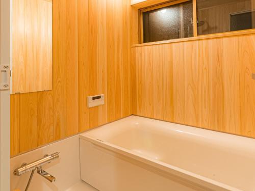 a bathroom with a white tub in a wooden wall at NIPPONIA Sado 佐渡相川 金山町 in Sado