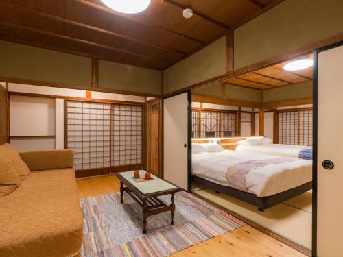 a bedroom with a bed and a couch and a table at NIPPONIA Sado 佐渡相川 金山町 in Sado