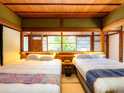 two beds in a room with two windows at NIPPONIA Sado 佐渡相川 金山町 in Sado
