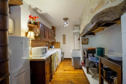 une cuisine avec des appareils électroménagers blancs et du parquet dans l'établissement Le Mirador Vue Sur La Dordogne, à Vézac