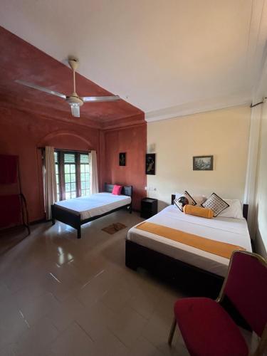 una camera d'albergo con due letti e una sedia di Sunbloom Hostel a Kandy