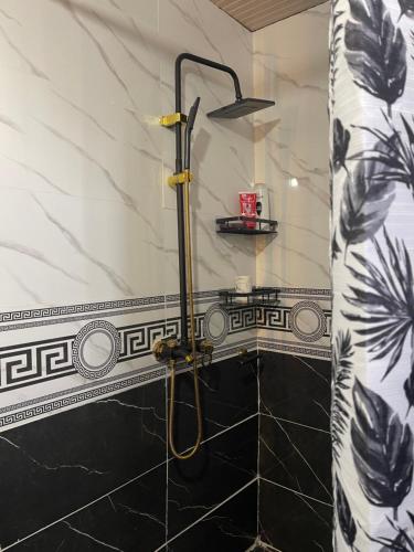 a shower in a bathroom with black and white tiles at Nomad place - horse riding tour Son-Kul in Dzhangyaryk