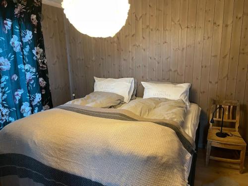 a bedroom with a bed with white sheets and a chandelier at MYLLA - New cabin - Sauna - Hike - Bike - Canoe- Fishing in Jevnaker
