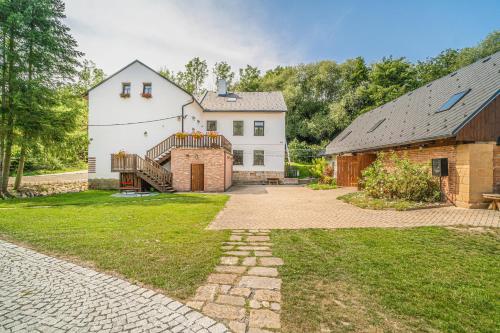 a large white house with a staircase and a barn at Buškovský mlýn 1580 in Dolní Bousov