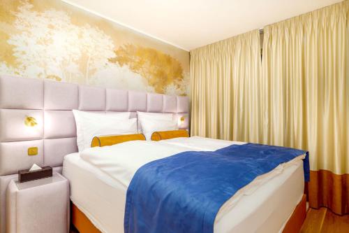 a bedroom with a large bed with a blue blanket at MOLO LIPNO RESIDENCE in Lipno nad Vltavou