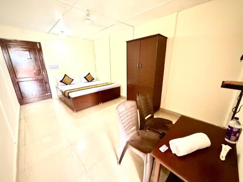 a room with a bed and a table and a desk at Hotel Kalka And Restaurant Patnitop in Kūd