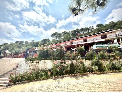 a garden with flowers on the side of a building at Hotel Kalka And Restaurant Patnitop in Kūd