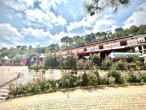 a garden with flowers in front of a building at Hotel Kalka And Restaurant Patnitop in Kūd