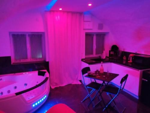 a purple room with a tub and a table in it at La suite miroir, love room avec jacuzzi in Bouc-Bel-Air