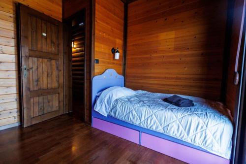 a small bed in a room with a wooden wall at Villa PARADISE in Néa Michanióna