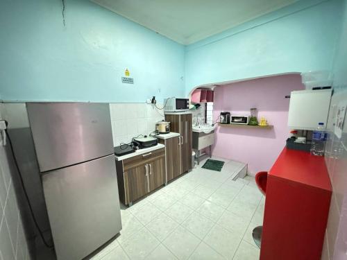 a small kitchen with pink walls and stainless steel appliances at Darul Salam Orkid Inn in Dungun