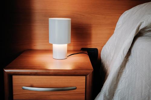 a lamp on a night stand next to a bed at Hotel Eldorado in Apiro