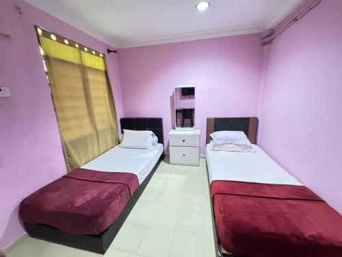 two beds in a room with purple walls at Darul Salam Orkid Inn in Dungun